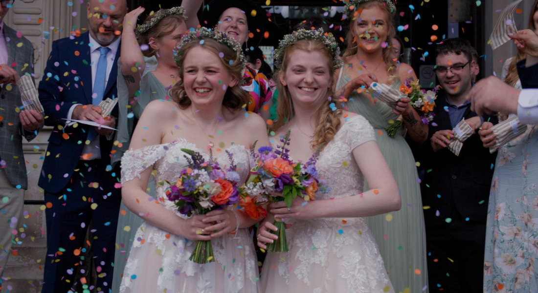 Image shows couple Fran and Izzy getting confetti thrown on them during their wedding at the town hall in Eastbourne, East Sussex