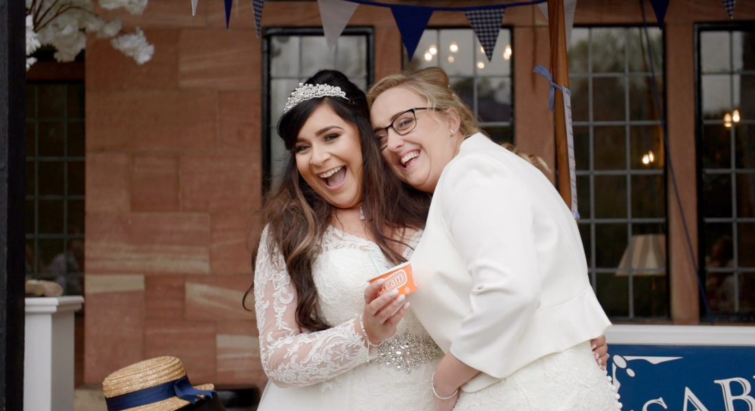 Image shows couple Sheryl and Jodie smiling holding ice cream during their wedding at Inglewood Manor, near Ellesmere Port