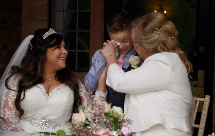 Image shows brides Sheryl and Jodie, with their son who is emotionally crying on their wedding day